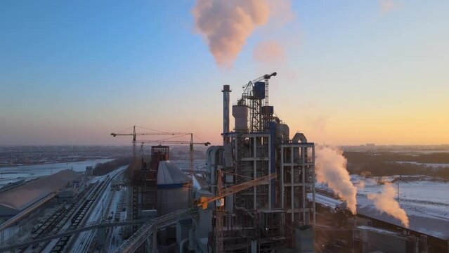 Aerial view of cement factory tower with high concrete plant structure at industrial production area at sunset. Manufacturing and global industry concept