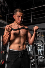 High quality photography. A muscular man training with a barbell. Latin man making a lot of effort when lifting a barbell with weight. A shirtless man in the gym.