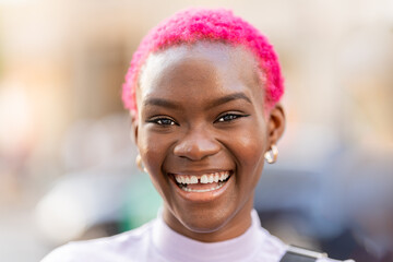 African woman with short pink hair smiling