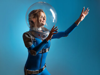 Fantastic astronaut costume in retrofuturism style. A young beautiful blonde in a blue suit with a spherical helmet. pioneer of space exploration, atomic era, retro style © Ulia Koltyrina