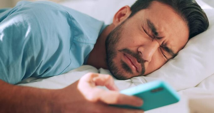 Wake up, tired and text with man in bed looking at phone messages, social media or internet app. Sleep, online and exhausted with young guy focus on screen while lying in bedroom at home