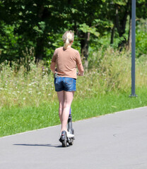 Fototapeta premium A girl rides a scooter along the road