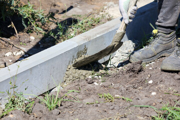 A worker is installing a concrete curb at a construction site.