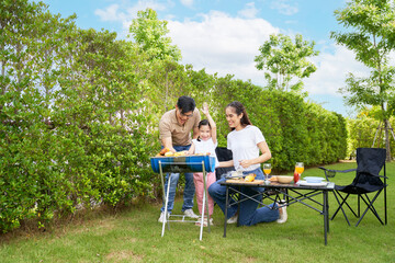 Family picnic time concept , Parent and child grilling barbeque and vegetable on frame on green yard of day time