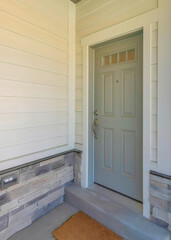 Vertical Gray front door of a townhome with glass panes and doormat