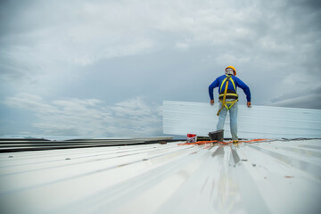 Asian construction worker holding metal sheet installation tool to build industrial factory roof