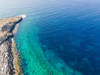 Obraz premium Marine background of the Mediterranean sea surface. Top view from a drone. Stone cape of the island. Exotic water landscape. Natural tropical paradise. Camping in Cyprus.