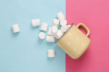 Cup with marshmallows top view on pink blue background