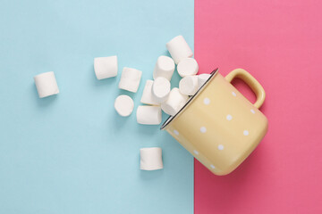 Cup with marshmallows top view on pink blue background