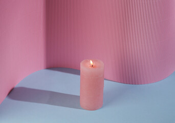 Flaming aroma candle on a blue-pink background with a shadow. Creative layout. Minimal composition