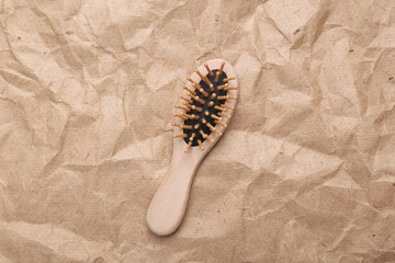 Wooden hair brush on crumpled craft paper background. Zero waste simple creative concept. Trendy wooden eco thing. Top view, Flat lay