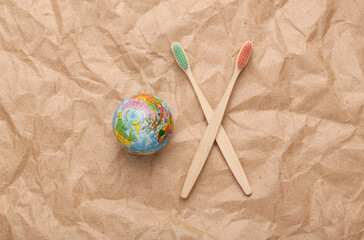 Wooden toothbrushes with globe on crumpled craft paper background. Zero waste simple creative concept. Trendy eco things. Top view, Flat lay