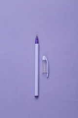 Purple pen with a cap on a purple background. Minimal concept
