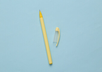 Yellow pen with a cap on blue background. Minimal concept