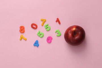 Education concept. Apple and colored numbers on a pink background. top view