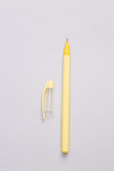 Yellow pen with a cap on a gray background