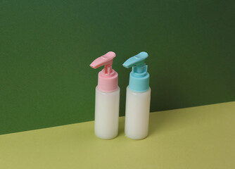 Aesthetic beauty still life. Bottles of cream or liquid soap on two tone green background.