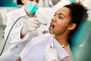 Mid adult black woman during dental procedure at dentist's office.