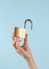 Open metal lock in female hand on a blue background.