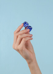 Blue dice in female hand on a blue background.