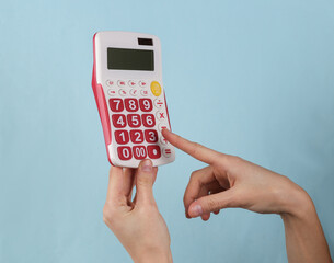 White calculator with pink buttons in female hands on a blue background.