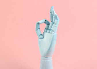 Wooden hand shows okay gesture on pink background