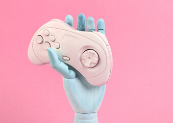 Wooden hand holds gamepad on pink background © splitov27