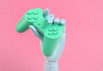 Wooden hand holds pink gamepad on pink background © splitov27