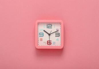 Square alarm clock on a pink background. Top view