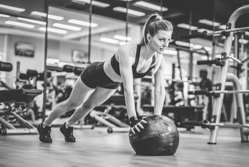 Fototapeta na wymiar Slim fit Woman push ups with medicine ball in the gym. Functional training