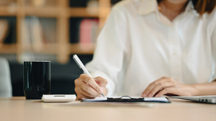 Beautiful female employee using laptop computer at bright modern corporate office