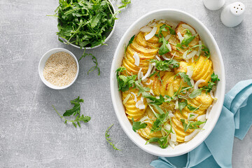 Baked potato with onion and fresh arugula, top view
