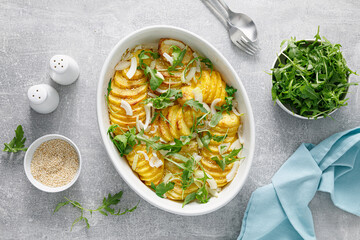 Baked potato with onion and fresh arugula, top view