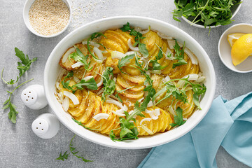Baked potato with onion and fresh arugula, top view