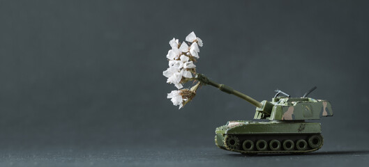 Model toy of battle tank firing flowers from the barrel. Peace and no war concept. Military pancer...