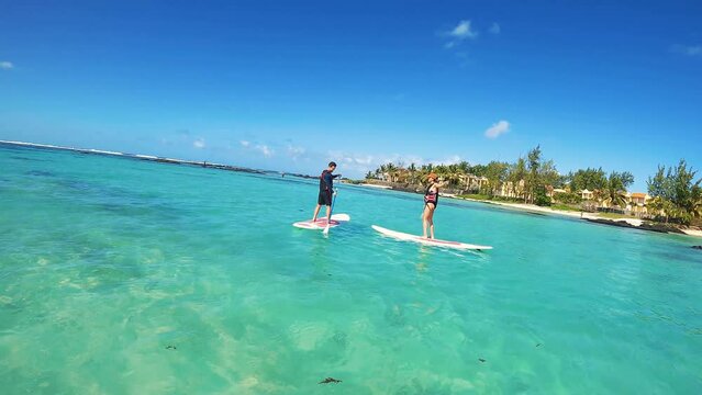 Couple paddling on two Stand up paddles in Mauritius, Belle Mare