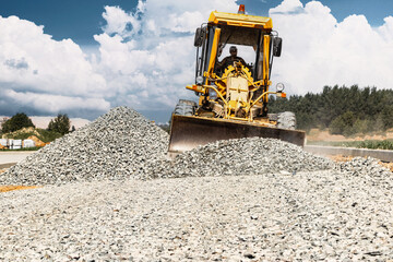 Road grader at the construction site. Powerful construction machine for ground leveling and...