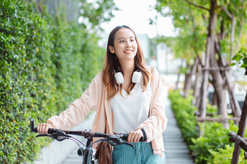 Happy Asian young woman walk and ride bicycle in park, street city her smiling using bike of transportation, ECO friendly, People lifestyle concept..