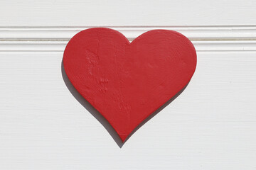 Red wooden heart on white wall background