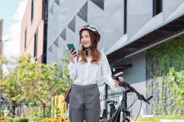 Fototapeta na wymiar Asian businesswoman hold mobile smart phone go to office work at modern city street with bicycle, Eco friendly in the morning business female using bike concept.