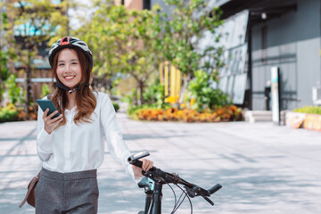 Asian businesswoman hold mobile smart phone go to office work at modern city street with bicycle, Eco friendly in the morning business female using bike concept.