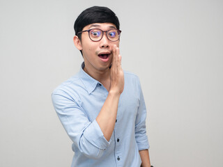 Young asian man wear glasses gesture whisper to you isolated