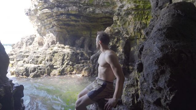 Traveling young man discovering new place.
The young man entering the sea cave sees the magnificent natural scenery and is impressed.
