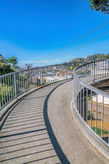 Obraz premium Raised concrete walkway over a road with view of houses in a residential area