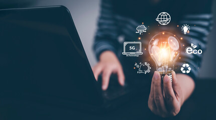 Man hand hold light bulb with icons work on the desk, Creativity and innovation are keys success. Concept of new idea and innovation with icons and light bulbs, Save the money, Freedom of thought.