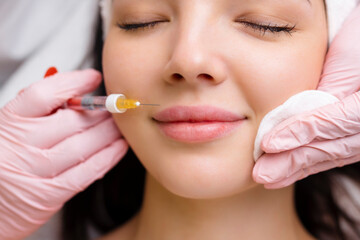 lip shape correction procedure in a cosmetology salon. The specialist makes an injection on the...