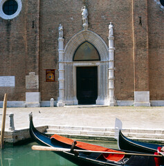 Fototapeta na wymiar Venezia. Gondola e portale della facciata della basilica di Santa Maria Gloriosa dei Frari.