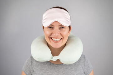 Smiling caucasian woman with travel pillow and sleeping mask isolated on white background.