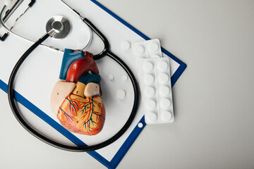 Stethoscope, clipboard and heart model on a table