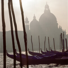 Venezia. La Salute in controluce con gondole sul Canal Grande, nel caligo. © Guido